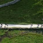 drone photo of muslim hikers in english countrside, beautiful, sunny day, green mountains, stone walls, white paths.