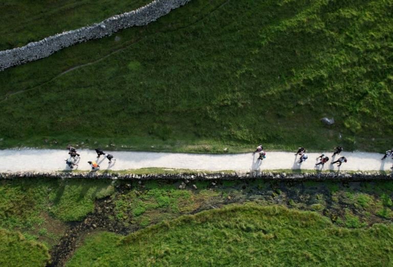 drone photo of muslim hikers in english countrside, beautiful, sunny day, green mountains, stone walls, white paths.