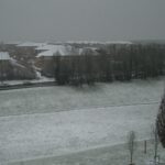Photo of a snowy field in Bristol, dusk, street lights on.