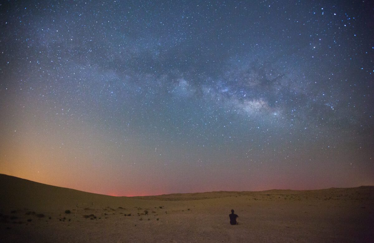 milky way at night, man sitting looking at the night sky
