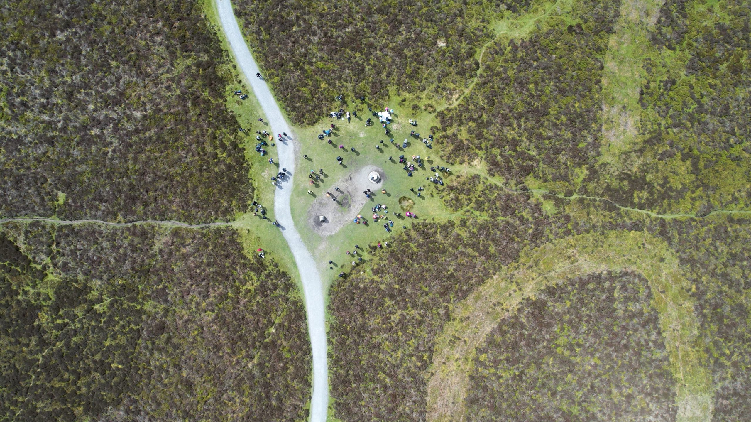 An aerial drone photograph by Mohammed Ismail showing a top-down view of people gathered on a moorland path, demonstrating high-resolution aerial cinematography and site documentation capabilities.