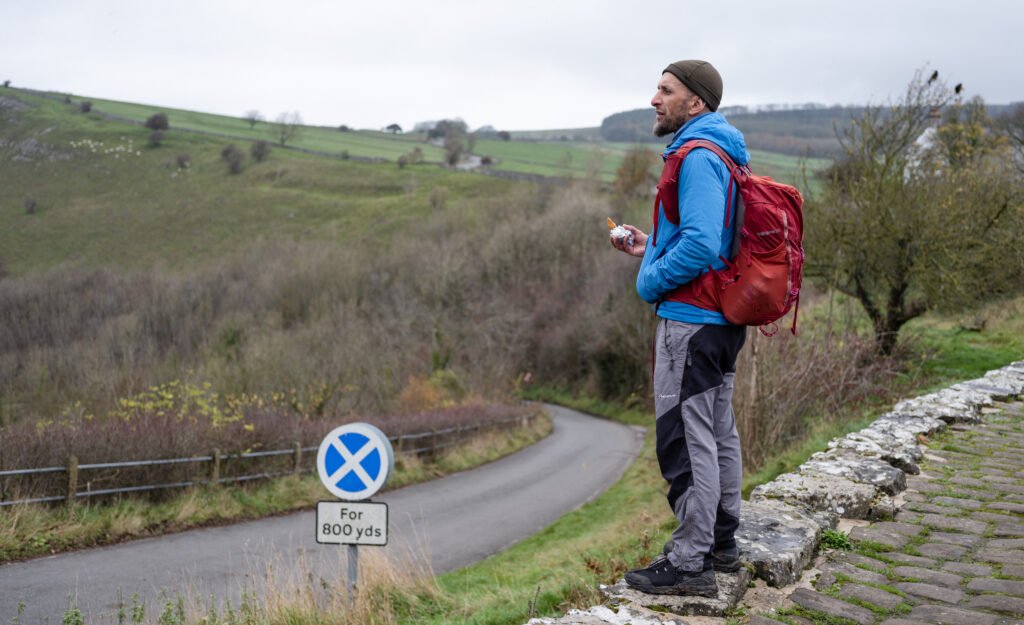 Hiker standing on a stone ledge taking a break during the Monsal Trail walk in the Peak District.