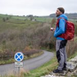 Hiker standing on a stone ledge taking a break during the Monsal Trail walk in the Peak District.
