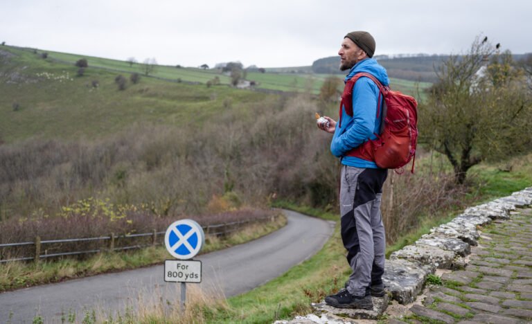 Hiker standing on a stone ledge taking a break during the Monsal Trail walk in the Peak District.
