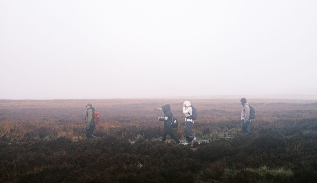 Hikers walking single file across misty moorland during the Padley Gorge and White Edge walk in the Peak District.