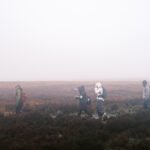 Hikers walking single file across misty moorland during the Padley Gorge and White Edge walk in the Peak District.